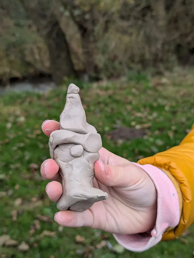 Niewielki gliniany stworek trzymany w dłoni podczas jesiennego działania.